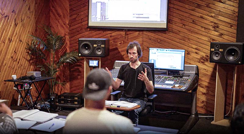 An instructor at the console explaining a mix decision to a student